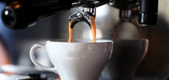macchinetta del caffè che riempie la tazzina in ceramica