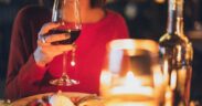 cena a lume di candela con donna che beve vino rosso